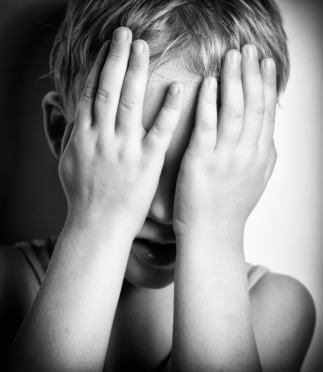 BW portrait of sad crying little boy covers his face with hands